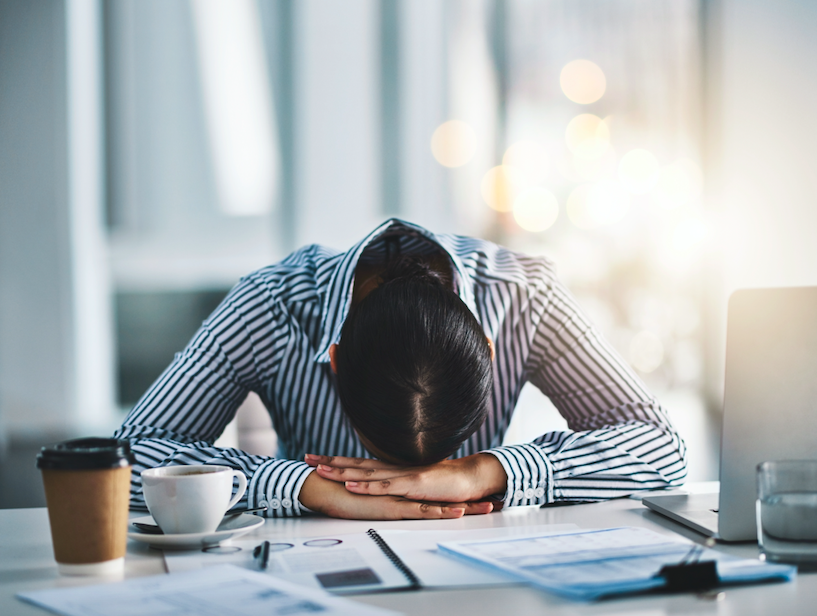 Young professional female suffering from employee burnout with head on desk