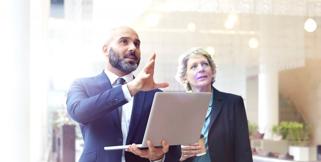 Facilities Manager with laptop reviewing workplace with a colleague